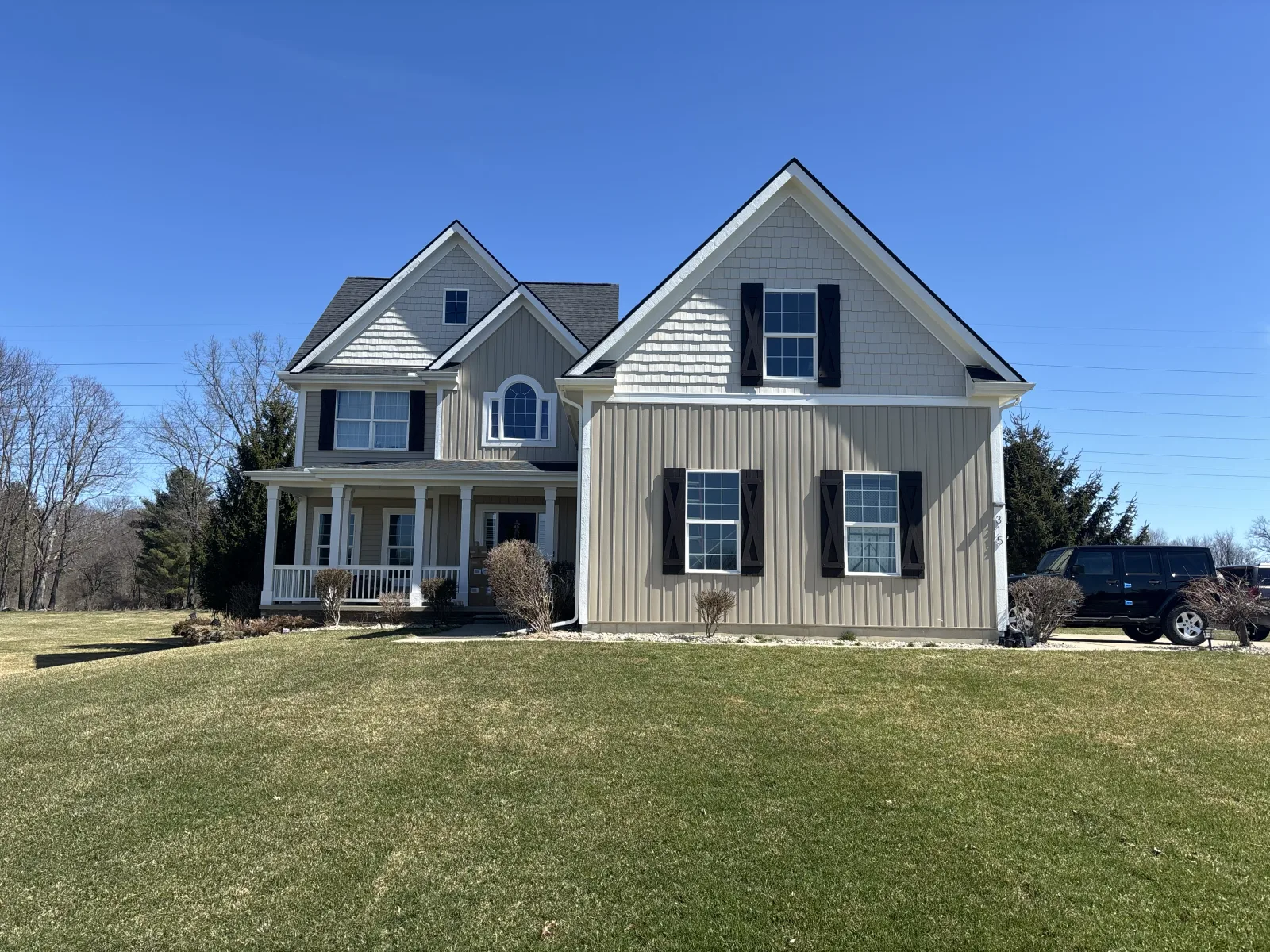 White home with mature trees and a completed roof and gutter system near Okemos, MI